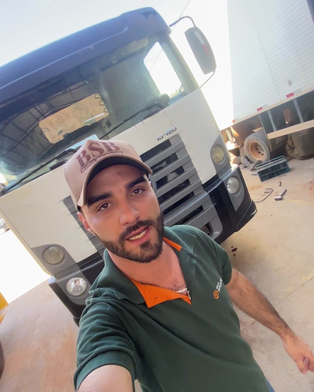 Integrante da equipe com o uniforme da oficina, em frente a um caminhão